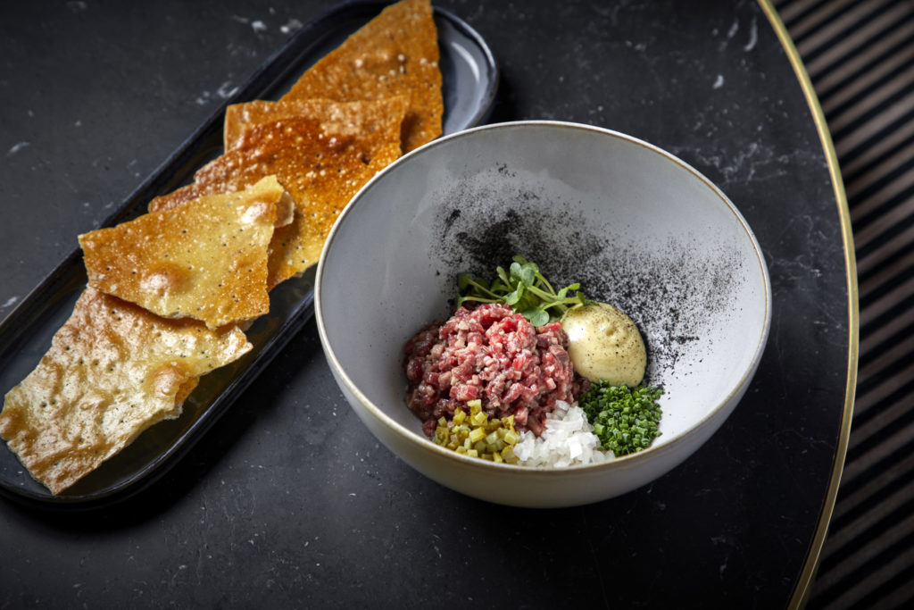 Servers mix up the ingredients of the beef tartare tableside.